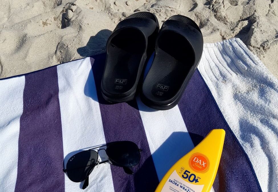 sunscreen sunglasses and a towel on the beach