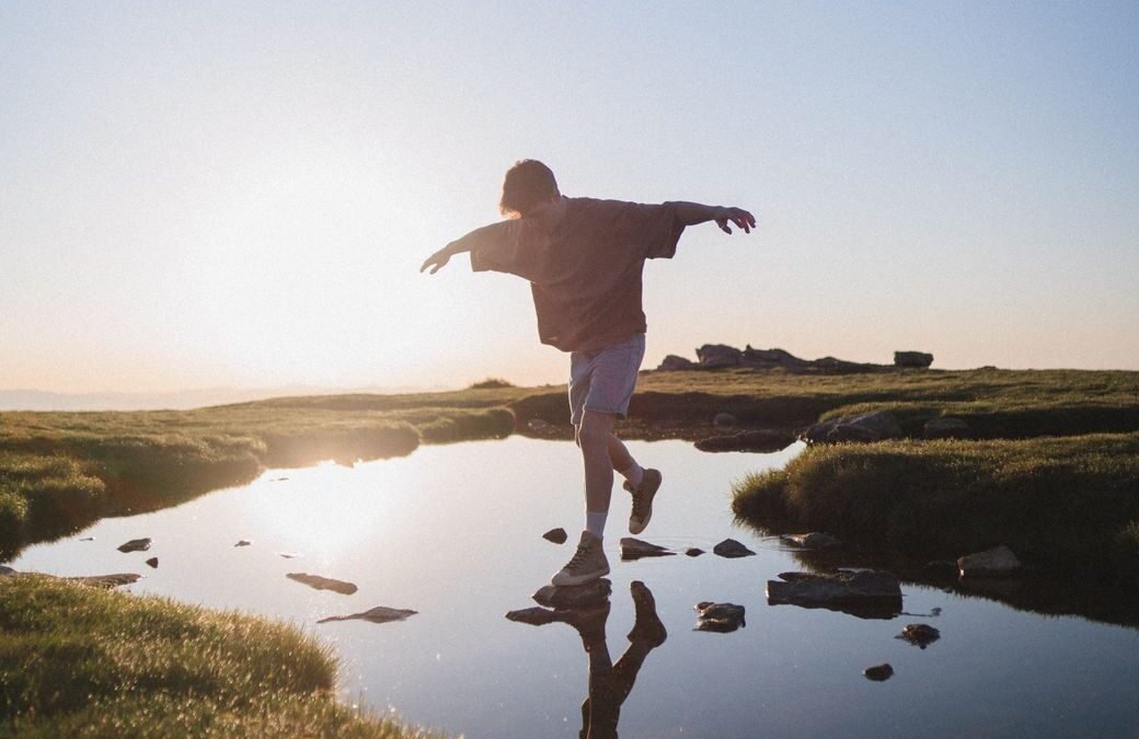 man jumping on rocks over a river